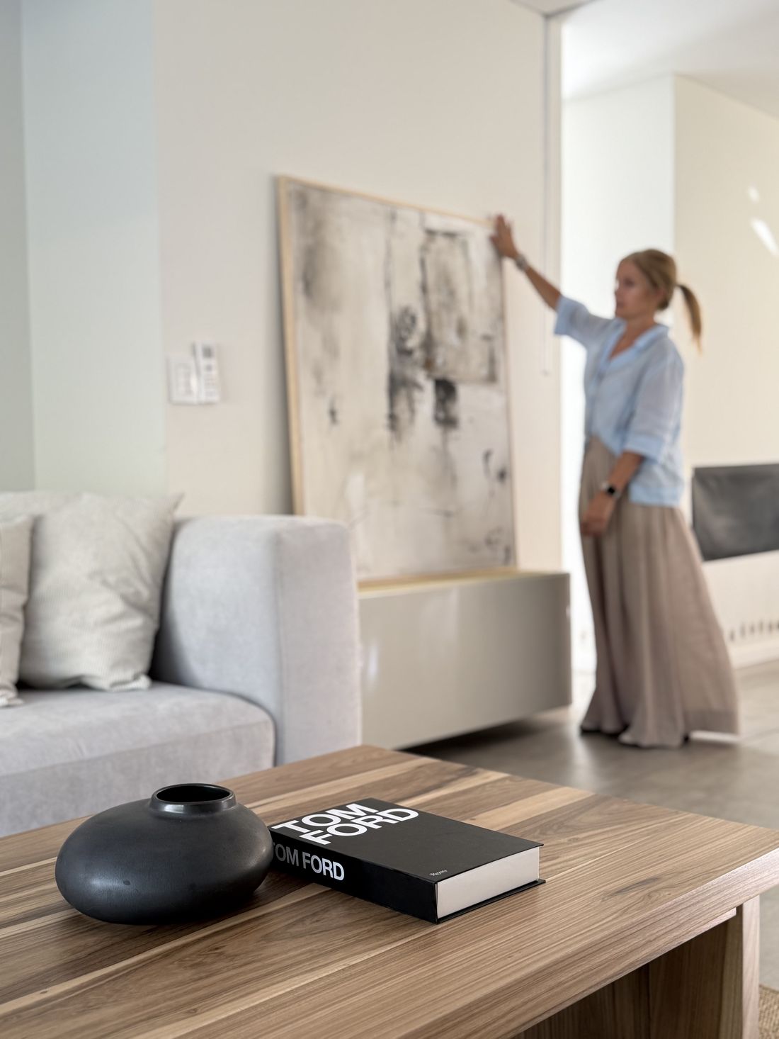 Obra original integrada en un living, junto a una mesa ratona con objetos de decoración