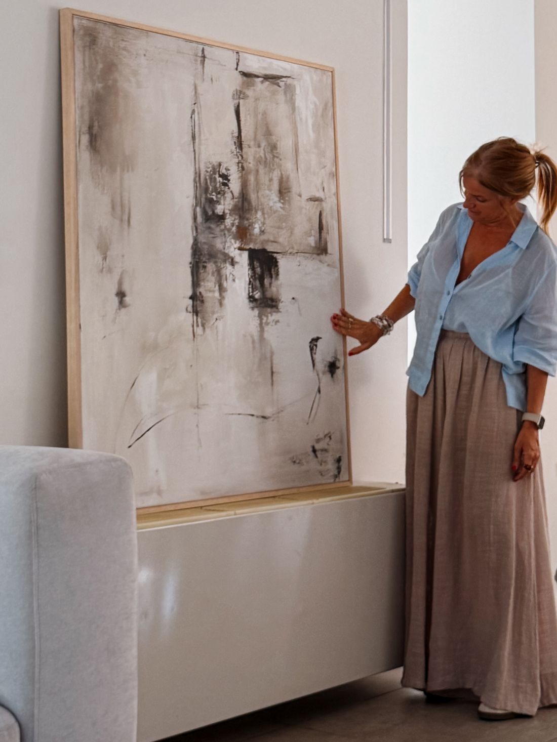 Vero Larraburu junto a una de sus obras originales, de gran formato y enmarcada en madera clara