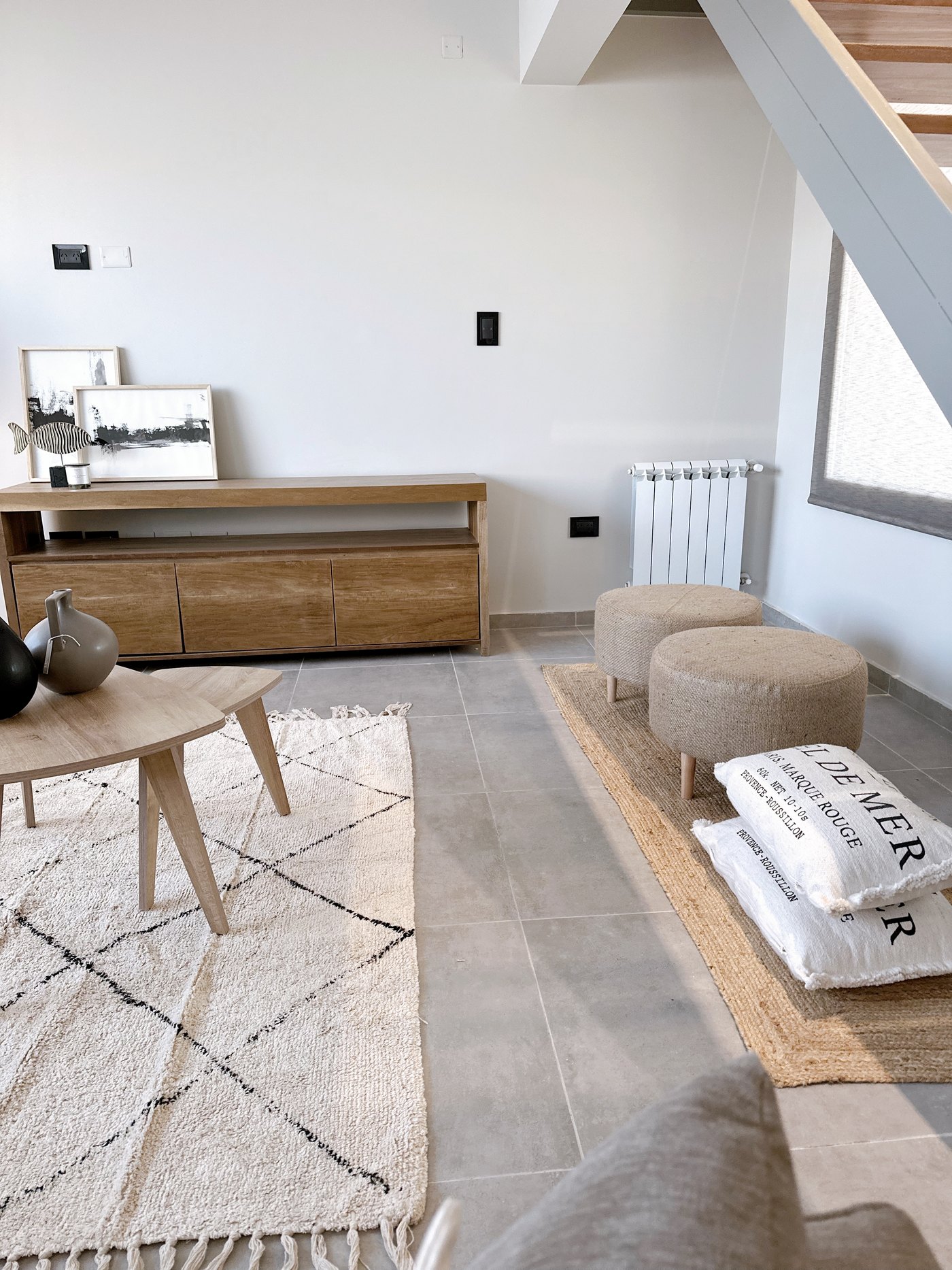 Living con estilismo de home staging: mesas ratonas de madera, alfombras naturales y puffs de yute